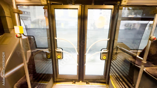  Interior view of public bus doors with handrails and steps leading outside.