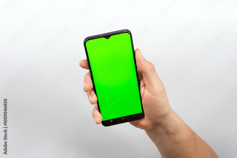 Phone screen is green chroma key. Green smartphone screen. Footage for mobile ads. Phone in the hand close up isolated at white background. Phone screen is green chroma key. Green smartphone screen. Footage for mobile ads. Phone in the hand close up isolated at white background.