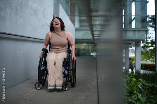 Smiling woman with a disability sitting in a wheelchair doing down the accessibility ramps