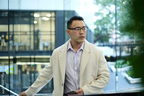 Asian man wearing cream coat walking in workplace photo