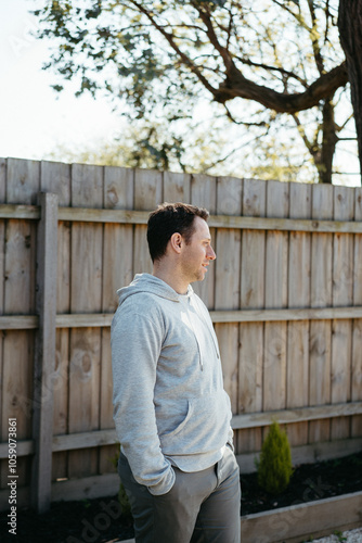 Middle-aged man standing in front of a wooden fence in the yard photo