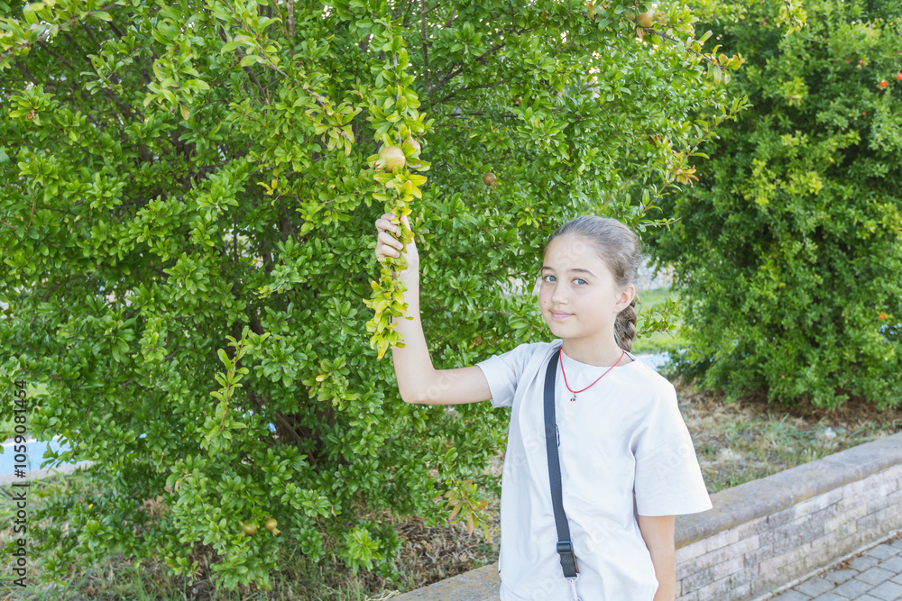 Child Holding a Pomegranate Branch in a Lush Garden