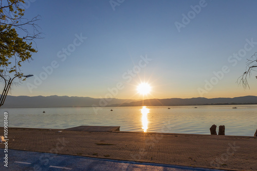 Stunning sunset over Doiran Lake, casting warm reflections across the calm waters and distant mountains. photo