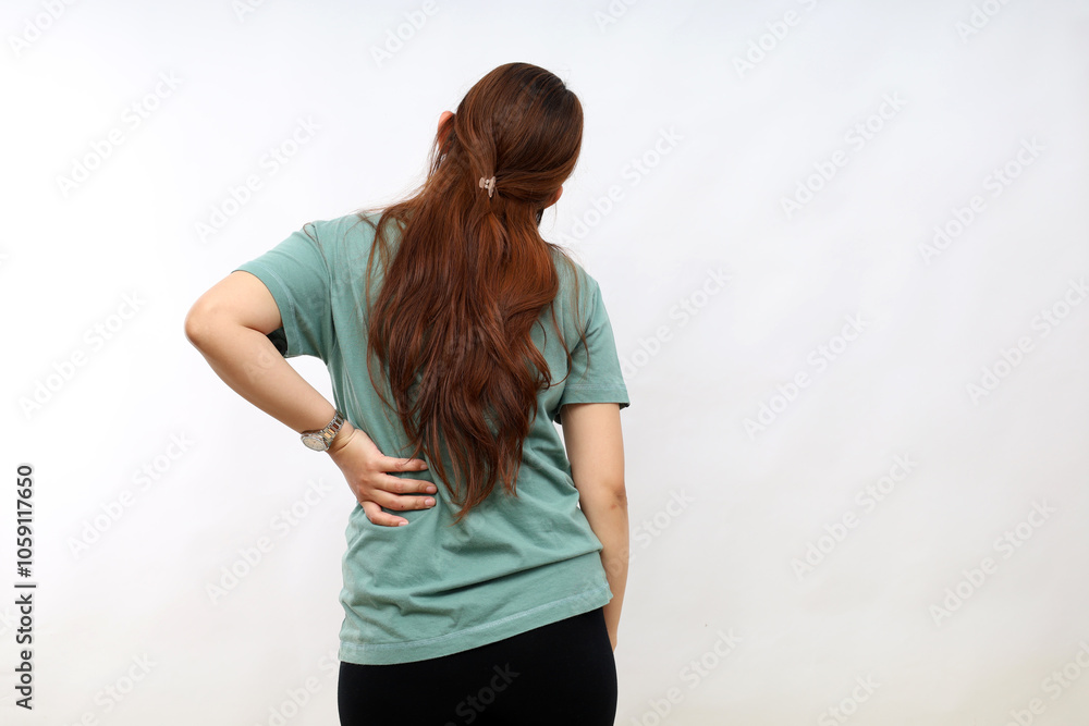 Young Asian woman in casual shirt suffering from pain in spine on white background Young Asian woman in casual shirt suffering from pain in spine on white background