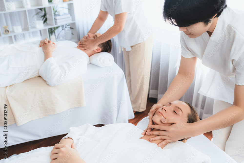 Caucasian couple enjoying relaxing anti-stress head massage and pampering facial beauty skin recreation leisure in dayspa modern light ambient at luxury resort or hotel spa salon. Quiescent Caucasian couple enjoying relaxing anti-stress head massage and pampering facial beauty skin recreation leisure in dayspa modern light ambient at luxury resort or hotel spa salon. Quiescent