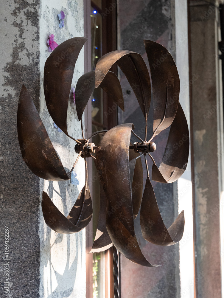 Old, rusty, curved blade fan, hanging on a building exterior Old, rusty, curved blade fan, hanging on a building exterior