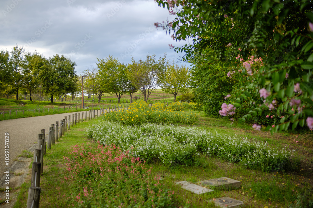 Pathway Through Blooming Flowers and Lush Trees on a Cloudy Day Pathway Through Blooming Flowers and Lush Trees on a Cloudy Day
