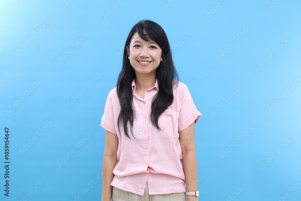 Pleased happy Asian woman shows teeth, expresses positive emotions, poses indoor with blank space for your promotional content. Isolated on blue background Pleased happy Asian woman shows teeth, expresses positive emotions, poses indoor with blank space for your promotional content. Isolated on blue background