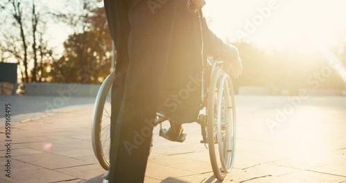 Hispanic man taking care of old disabled friend in wheelchair. Friends spending time together in autumn park. Healthcare, disability, mobility, friendship. Close up 4k shot