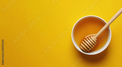 Natural honey in a bowl with a wooden dipper on a vibrant yellow background
