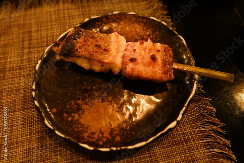 Close up of Japanese skewer of grilled eel fish on a black plate photo