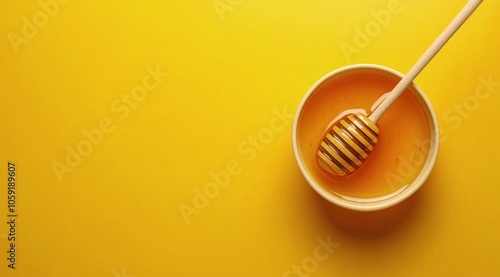 Natural honey in a bowl with a wooden dipper on a vibrant yellow background