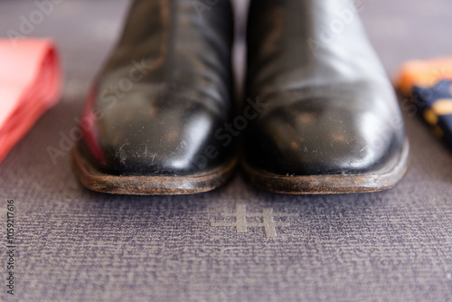 black boots with lightly scuffed toes sitting on grey fabric photo