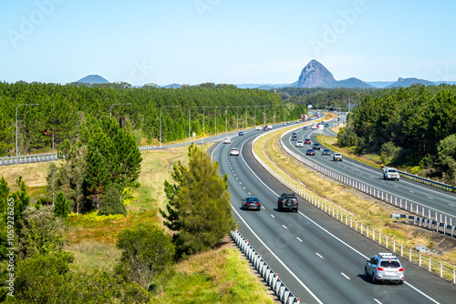 Vehicles driving the M1 Bruce Highway with glass house mountains in background.