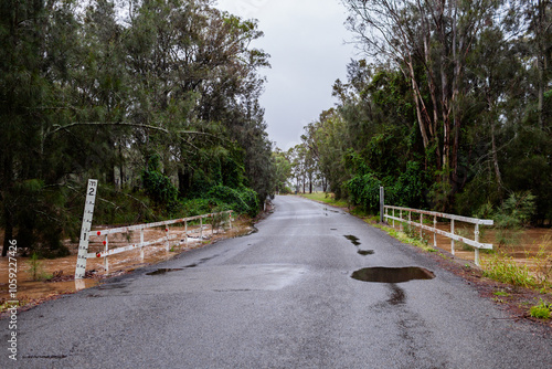 road over flooding creek with floodwater rising up to bridge photo