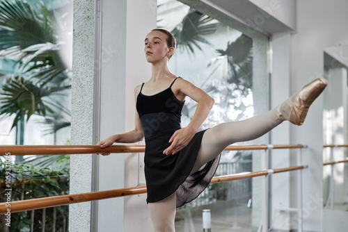 Photos Confident teenage ballerina effortlessly raising elegant leg performing adagio m