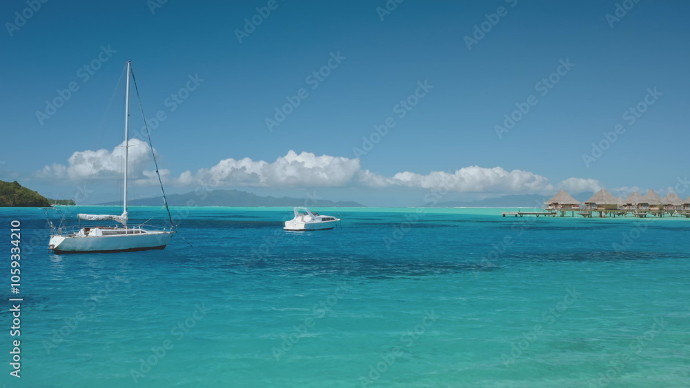 Two sailboats yachts anchored in calm turquoise water of tropical lagoon with overwater bungalows. French Polynesia Bora Bora stunning tropical paradise, perfect exotic summer travel luxury vacation. Two sailboats yachts anchored in calm turquoise water of tropical lagoon with overwater bungalows. French Polynesia Bora Bora stunning tropical paradise, perfect exotic summer travel luxury vacation.