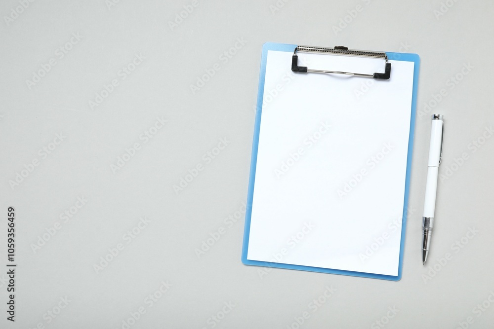 Clipboard with paper sheet and pen on gray background, top view. Space for text Clipboard with paper sheet and pen on gray background, top view. Space for text