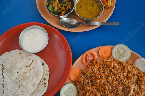 Overhead view of dal bhat tarkari set or rice and lentil soup, chicken biryani, juju dhau or yogurt and roti, authentic local Nepalese daily staple food photo