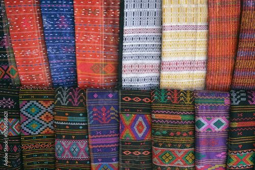 Rows of colorful traditional woven fabric called Ulos sold as souvenirs showing the authentic culture and heritage of the Batak indigenous people of Indonesia photo