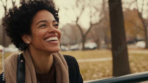 Woman with a black coat and a brown scarf is smiling