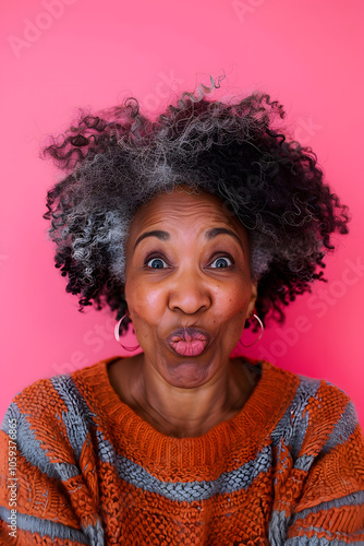 Portrait of senior black woman with funny face on pink background.