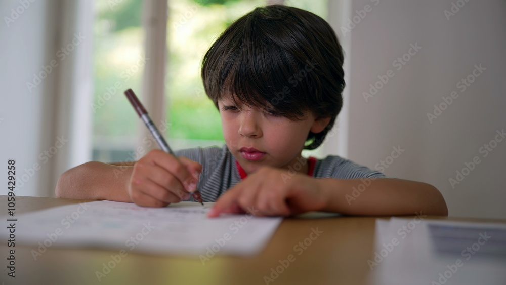 Boy sketching carefully with a marker, leaning on the table while intently drawing on paper, focused on creating his artwork Boy sketching carefully with a marker, leaning on the table while intently drawing on paper, focused on creating his artwork