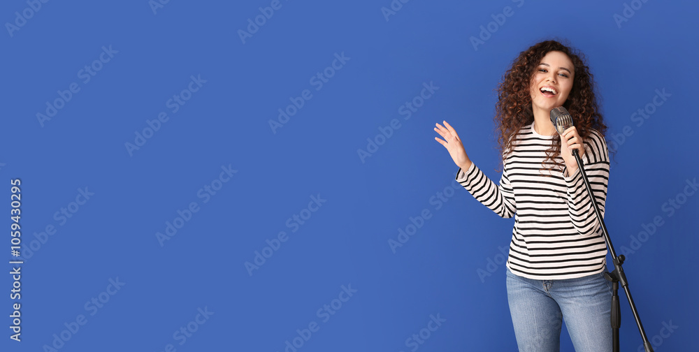 Young African-American woman singing on color background