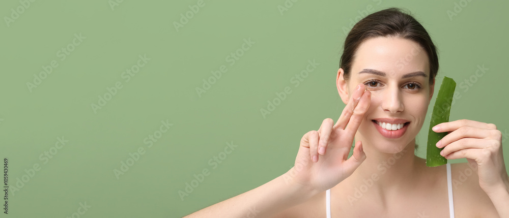 Fototapeta premium Beautiful young woman applying aloe vera with two fingers on green background