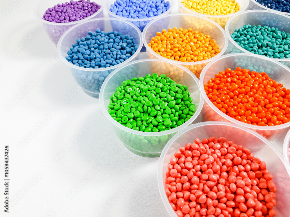 Various colored masterbatch granules in a cup on a white background.Polymer carriers of color pigments in the plastics industry Various colored masterbatch granules in a cup on a white background.Polymer carriers of color pigments in the plastics industry