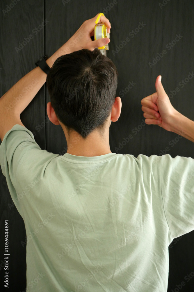 A young man trying to measure his height with a tape measure