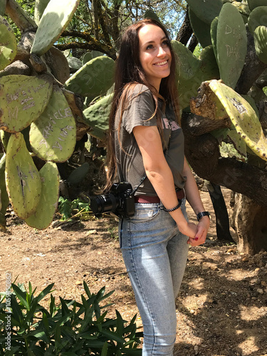 UGC, smiling girl with a camera on her shoulder surrounded by cactuses photo