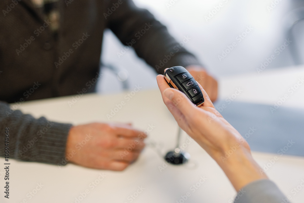 Saleswoman giving automobile key fob to client in dealership office Saleswoman giving automobile key fob to client in dealership office