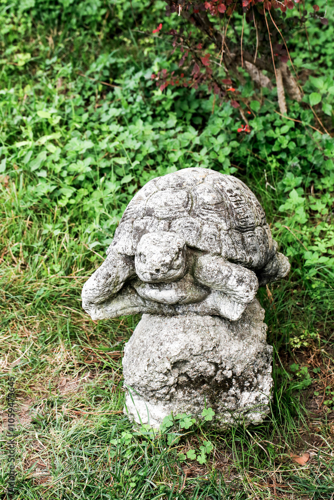 A beautifully crafted statue of a turtle perched atop a rock in a grassy area A beautifully crafted statue of a turtle perched atop a rock in a grassy area