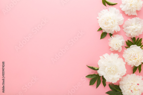 Fresh beautiful soft white peony flowers with green leaves on light pink table background. Pastel color. Closeup. Empty place for inspirational text, lovely quote or positive sayings. Top down view. photo