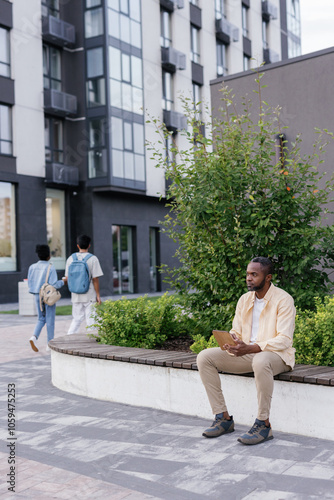 Man sitting on bench outdoors near office building photo