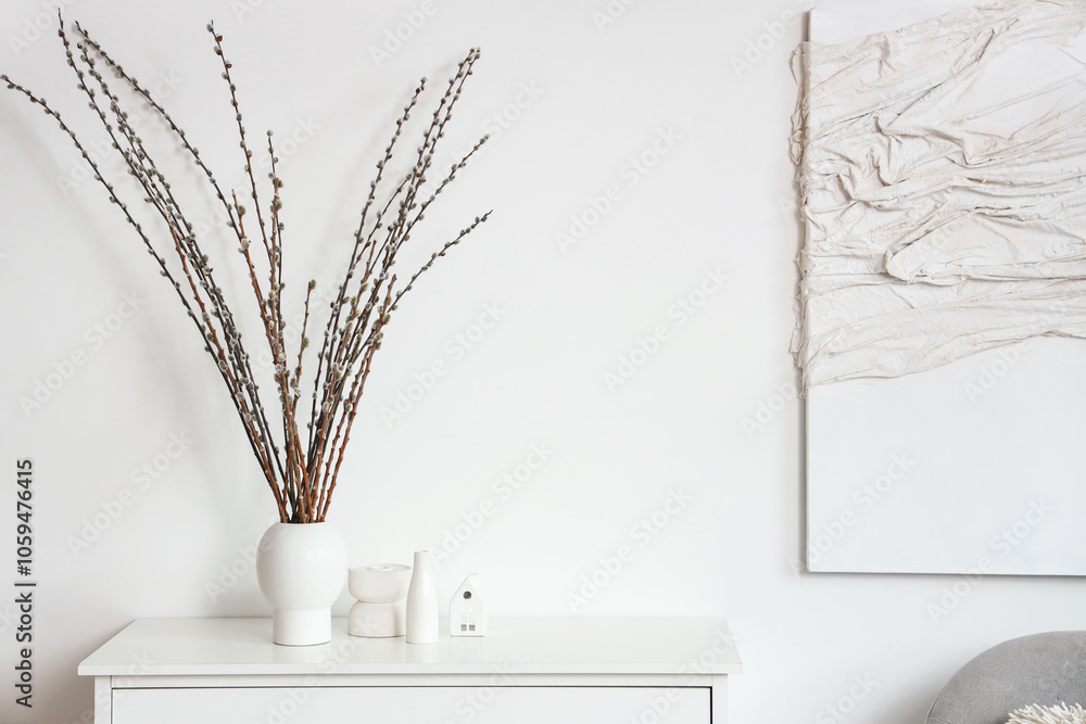 Vase with willow branches on commode in light living room Vase with willow branches on commode in light living room