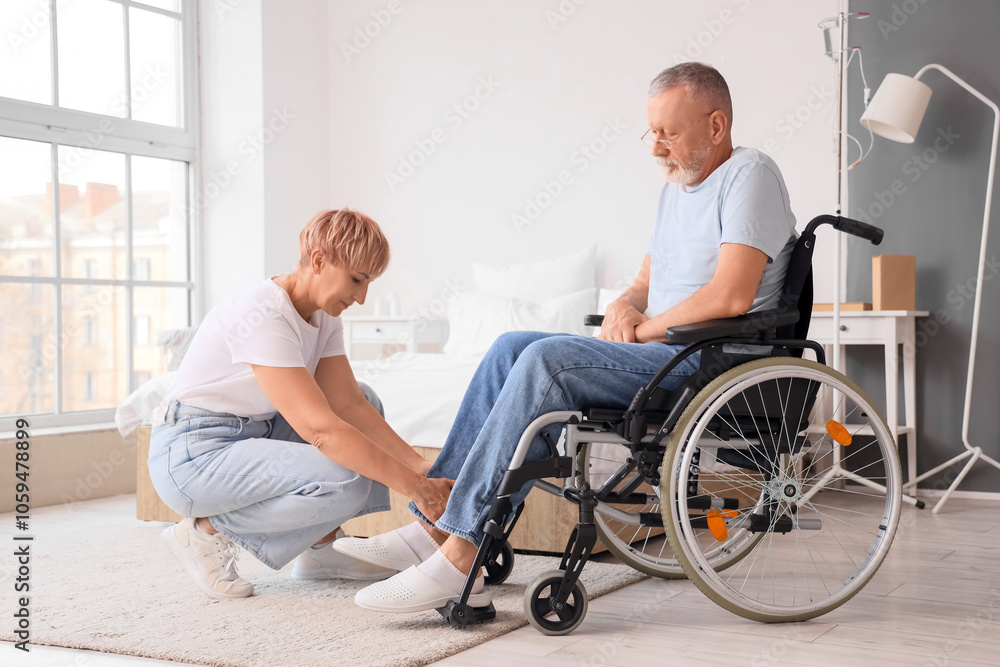 Mature woman helping her sick husband in wheelchair at home Mature woman helping her sick husband in wheelchair at home