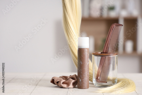 Hair spray with comb, strand and scrunchy on table in beauty salon