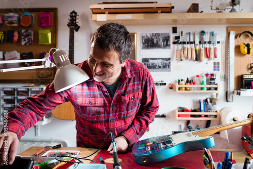 Happy guitar luthier working on small workshop photo