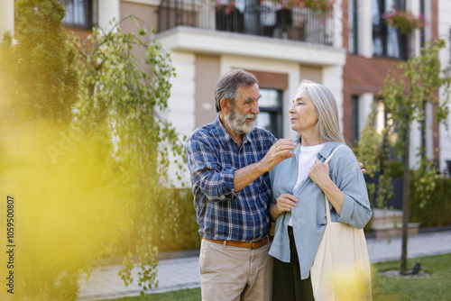 Elderly woman listening husband or boyfriend telling to her in yard photo