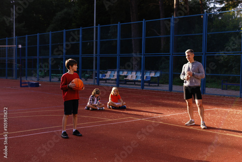 Schoolboy listening to coach while preparing to make basketball shot  photo