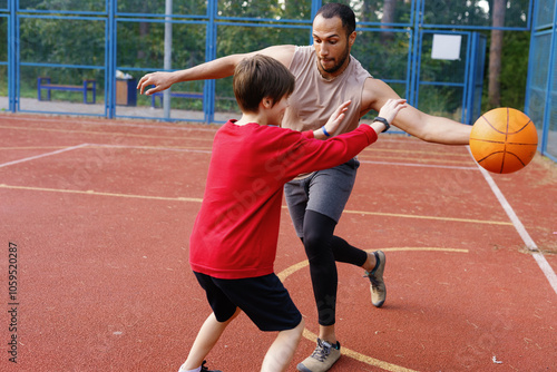 Boy trying to intercept pass of basketball from trainer during game