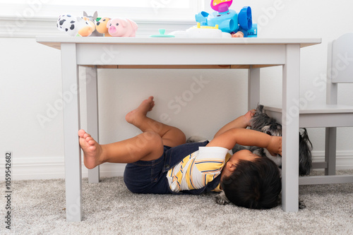 A boy playing with his dog under a table photo