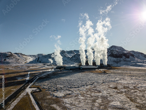 White steam billows from the geothermal power plant in Hellisheidi, Iceland, contrasting with the snowy peaks of Iceland's breathtaking winter scenery in this aerial photo