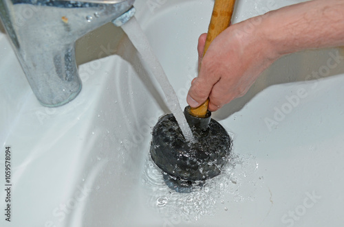 Plunger in men's hands. clearing a clog in the sink with a plunger. plumbing work . cleaning pipes from clogged drains. Hand holding a plunger. Plumbing problems