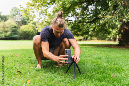 Man on Knees Setting Up Phone on Monopod photo