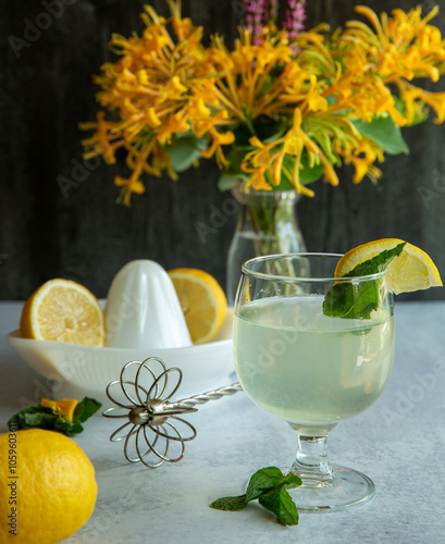 Fresh made mint lemonade with vintage cooking tools and bright yellow flowers
