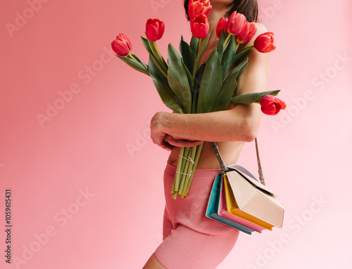 Woman Holding Colorful Tulips and Purse Against Pink Background photo