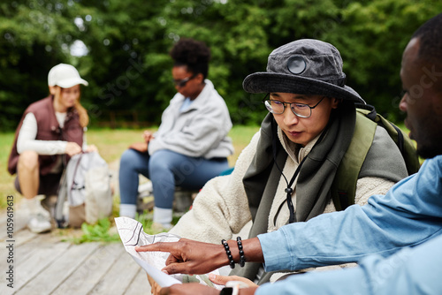 Portrait of tourists looking at map while exploring nature trails with multiethnic group of friends copy space photo